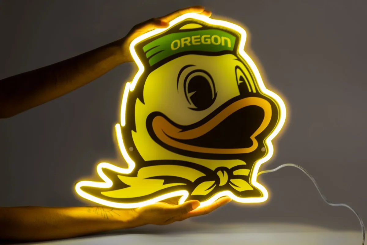 Saturday Neon Oregon Ducks 'O' LED neon sign held up by two hands — the brand's NCAA bestseller