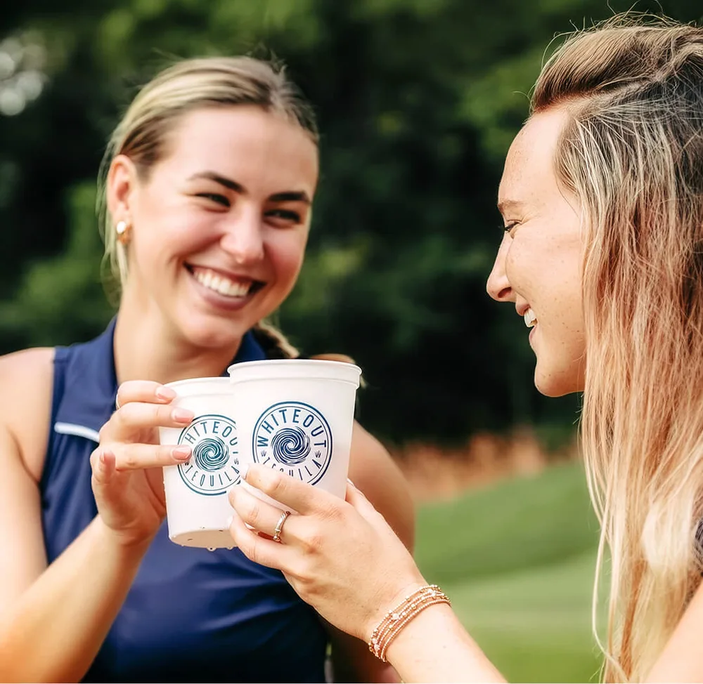 Two people outdoors holding Whiteout cups