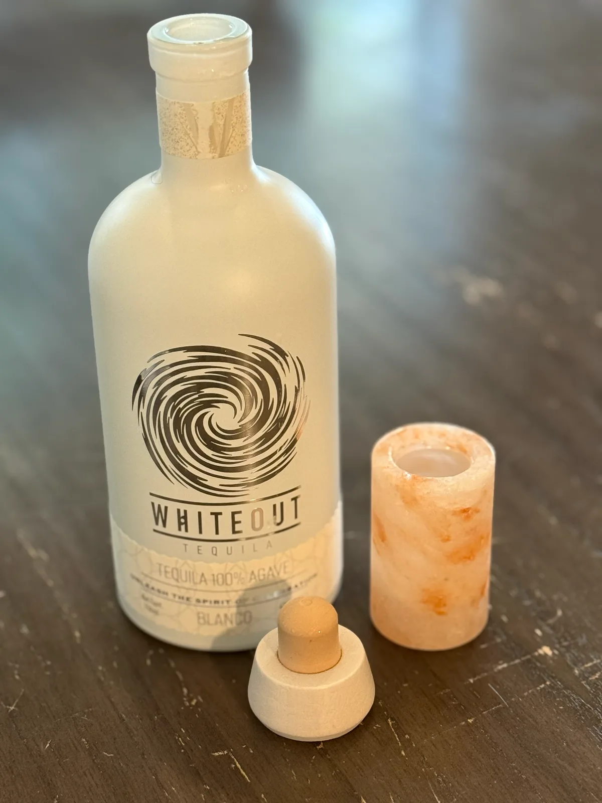 Our own bottle of Whiteout Tequila Blanco, opened, beside a Himalayan salt shot glass