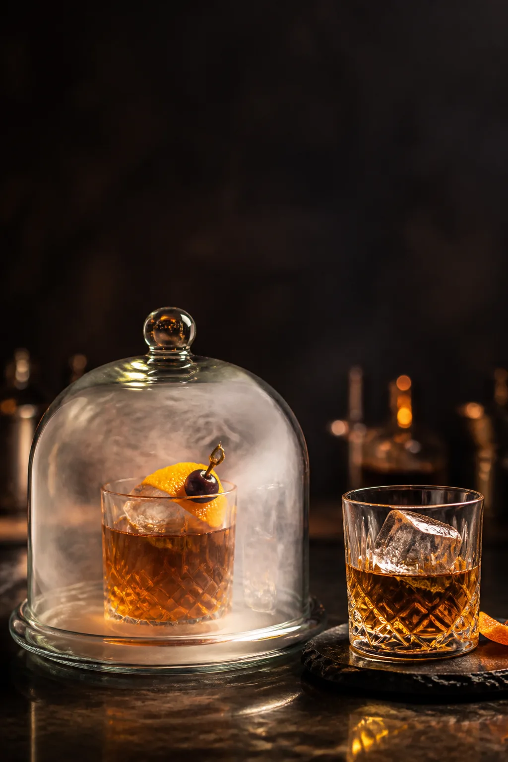 Smoked Old Fashioned under a glass cloche filling with swirling smoke